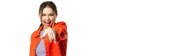 Erstaunte junge Frau in bauchfreiem Top und orangefarbenem Hemd, die mit dem Finger auf die Kamera zeigt, vereinzelt auf weißem Banner — Stockfoto