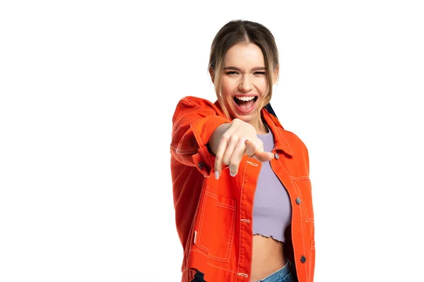 Amazed young woman in crop top and orange shirt pointing with finger at camera isolated on white — Stock Photo