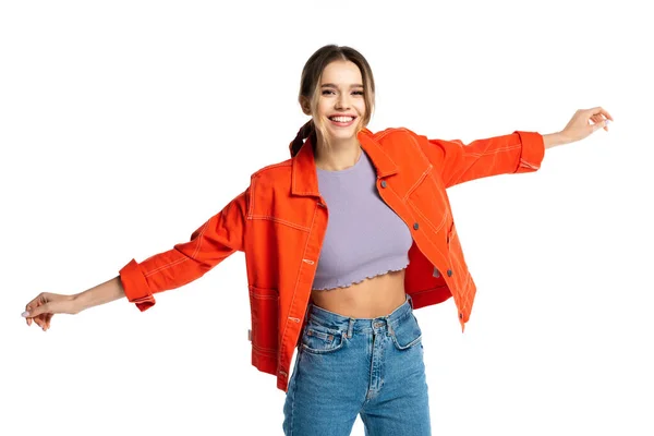 Heureuse jeune femme en crop top, jeans et chemise orange debout avec les mains tendues isolées sur blanc — Photo de stock