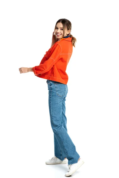 Pleine longueur de jeune femme positive en jeans et chemise orange debout isolé sur blanc — Photo de stock