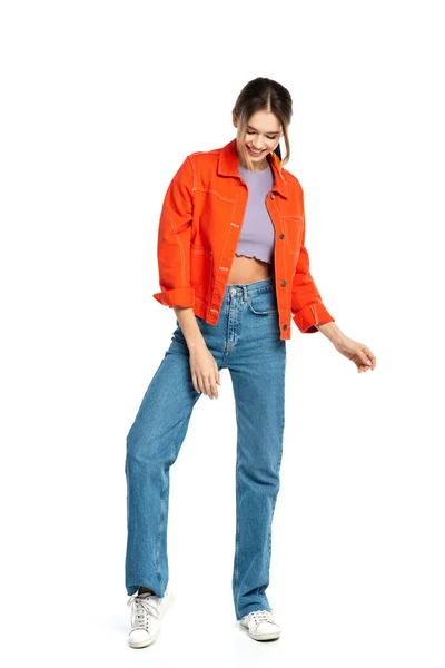 Pleine longueur de jeune femme heureuse en haut de culture et chemise orange debout isolé sur blanc — Photo de stock