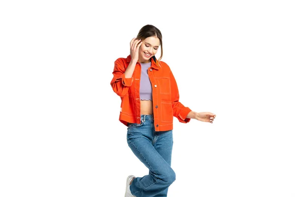 Улыбающаяся молодая женщина в джинсах, топе и оранжевой рубашке позирует изолированно на белом — стоковое фото