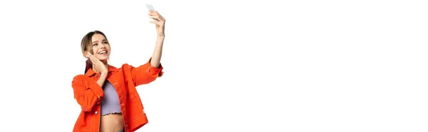 Glückliche junge Frau in bauchfreiem Top und orangefarbenem Hemd, Selfie auf Smartphone, Banner — Stockfoto