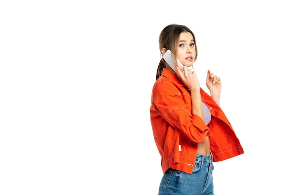 Inquiet jeune femme en jeans, crop top et chemise parler sur smartphone isolé sur blanc — Photo de stock