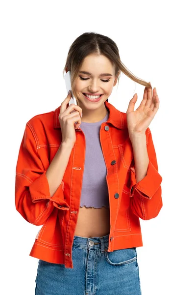 Mujer joven coqueta en la parte superior de la cosecha y camisa naranja hablando en el teléfono inteligente y morder los labios aislados en blanco - foto de stock