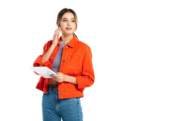 Mujer joven con camisa naranja y jeans usando tableta digital aislada en blanco - foto de stock
