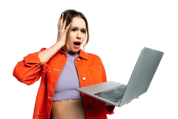 Donna scioccata in camicia arancione guardando computer portatile isolato su bianco — Foto stock