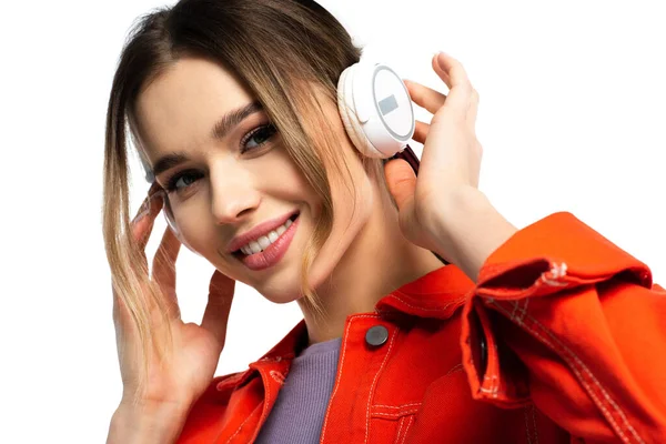Zufriedene Frau in orangefarbenem Hemd hört Musik in drahtlosen Kopfhörern isoliert auf weißem Grund — Stockfoto