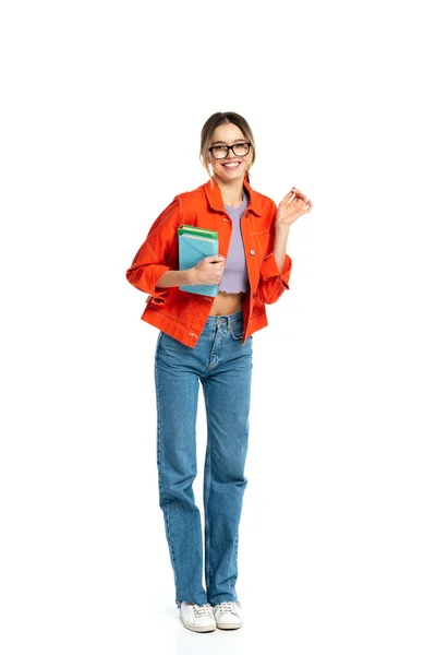 Larga duración de joven estudiante feliz en gafas sosteniendo libros aislados en blanco - foto de stock