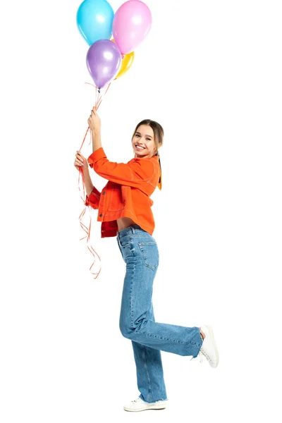 Volle Länge der fröhlichen jungen Frau in orangefarbenem Hemd mit bunten Luftballons isoliert auf weiß — Stockfoto