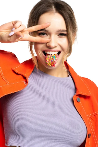 Young woman sticking out tongue with tasty sprinkles and showing peace sign isolated on white — Stock Photo