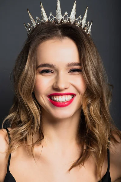 Positive young woman in tiara with diamonds on grey — Stock Photo
