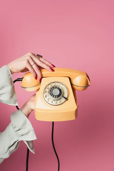 Vista ritagliata di donna in possesso di telefono retrò isolato su rosa — Foto stock