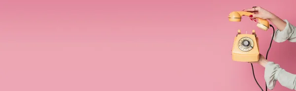 Vista cortada de telefone amarelo em mãos de mulher isolada em rosa, banner — Fotografia de Stock