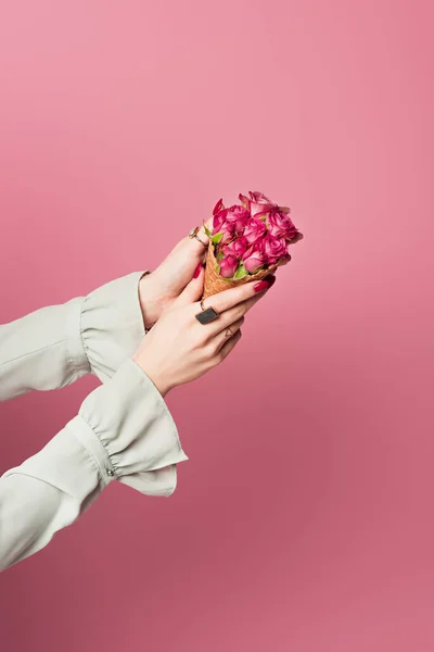 Vista cortada de mulher segurando cone de waffle e flores em mãos isoladas em rosa — Fotografia de Stock