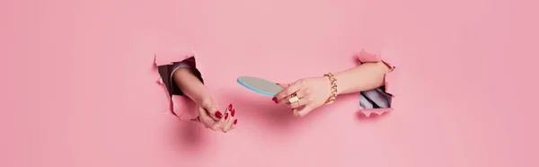 Vista cortada da mulher com acessórios segurando arquivo de unhas perto de fundo rosa com buracos, banner — Fotografia de Stock