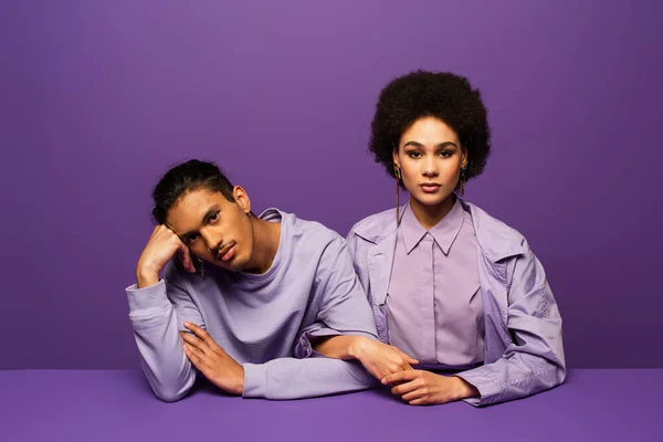 African american man and curly young woman looking at camera isolated on purple — Stock Photo