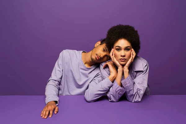 Stylish african american man leaning on young curly woman isolated on purple — Stock Photo
