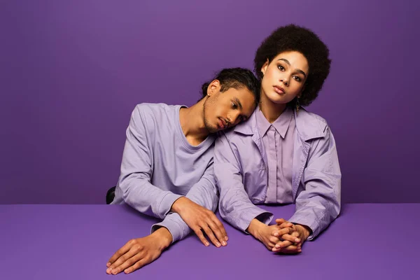 Fashionable african american man leaning on young curly woman isolated on purple — Stock Photo