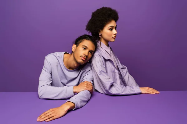 Young model leaning on curly african american woman isolated on purple — Stock Photo