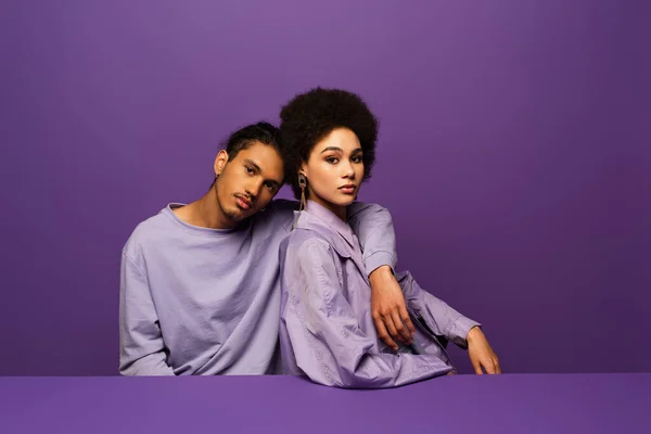 Young model hugging curly african american woman isolated on purple — Stock Photo