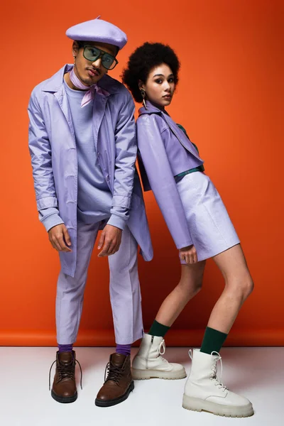 Full length of trendy african american woman and man posing on orange — Stock Photo