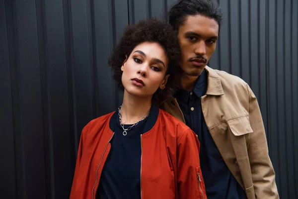 Hombre y mujer afroamericanos en chaquetas de moda posando afuera - foto de stock