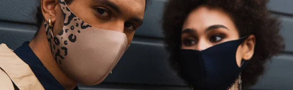 Femme afro-américaine floue et homme élégant dans des masques de protection à la mode, bannière — Photo de stock