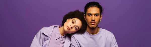 Young african american leaning on man isolated on purple, banner — Stock Photo