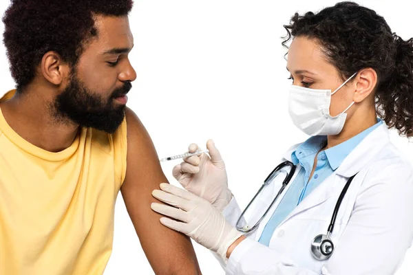 Médico afro-americano em máscara médica fazendo vacinação de paciente isolado em branco — Fotografia de Stock