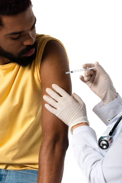 Médico en guantes de látex inyectable con vacuna a paciente afroamericano aislado en blanco - foto de stock