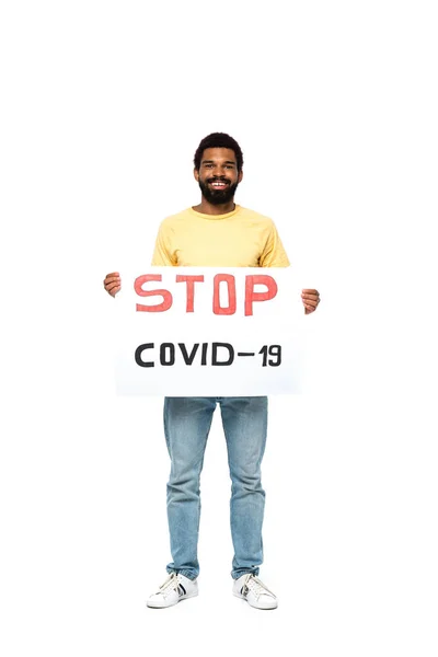 Cartel de hombre afro-americano positivo con letras stop covid-2019 sobre fondo blanco - foto de stock