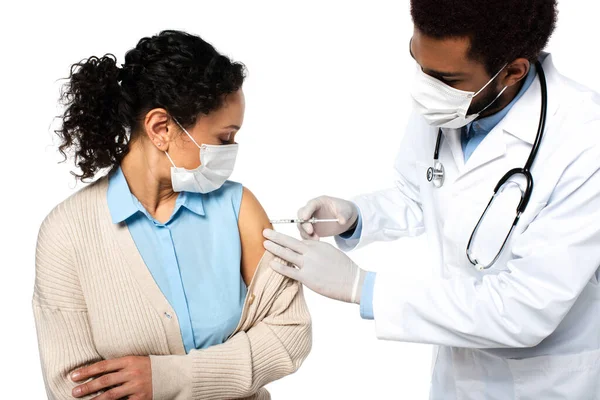 Médecin afro-américain sous masque médical faisant l'injection de vaccin au patient isolé sur blanc — Photo de stock