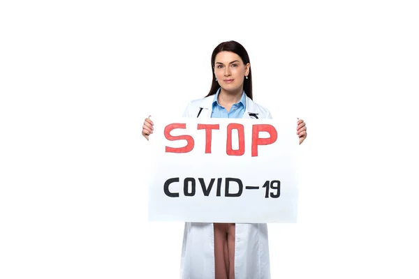 Médico morena sosteniendo pancarta con tope covid-2019 letras aisladas en blanco - foto de stock