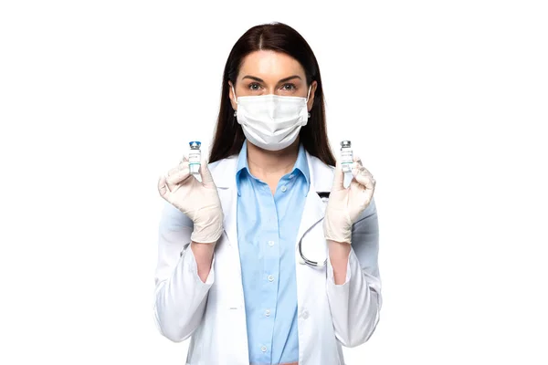 Medico in maschera medica che tiene vasetti con vaccino isolato su bianco — Foto stock