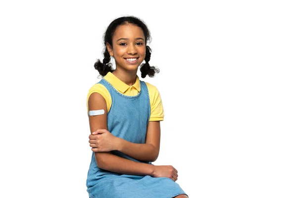 Cheerful african american kid with adhesive patch on arm looking at camera isolated on white — Stock Photo