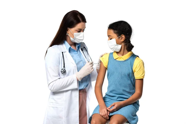 Kinderarzt in medizinischer Maske injiziert Impfstoff an afrikanisch-amerikanisches Kind isoliert auf weiß — Stockfoto