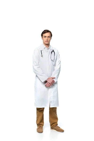 Доктор в белом халате смотрит на камеру на белом фоне — стоковое фото