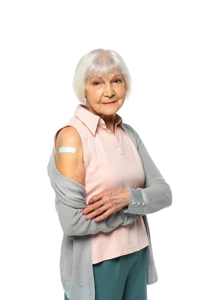 Пожилая женщина с клеевым пластырем на руке, смотрящая на камеру, изолированную на белом — стоковое фото