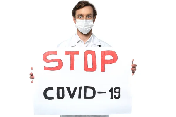 Placard con letras stop covid-2019 en manos del médico en máscara médica aislada en blanco - foto de stock