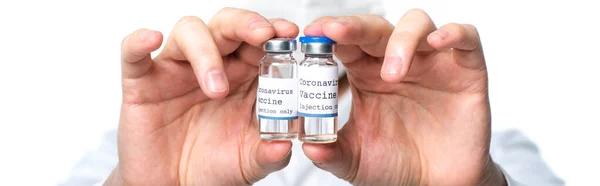 Обрезанный вид банок с вакциной в руках врача на размытом фоне изолирован на белом, баннер — стоковое фото