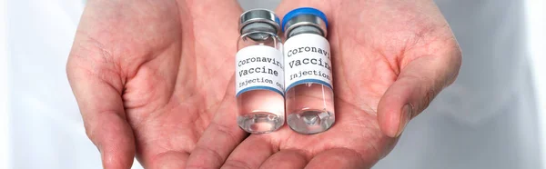 Обрезанный вид коронавирусной вакцины в руках врача, изолированного на белом, баннер — стоковое фото