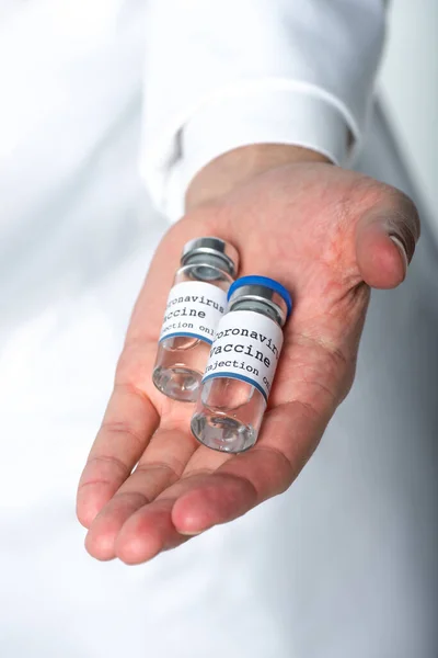 Vista recortada de frascos con vacuna contra el coronavirus en la mano del médico desenfocado aislado en blanco - foto de stock