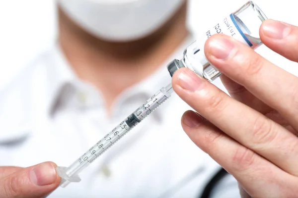 Vista de cerca de la jeringa y la vacuna en manos de un médico borroso aislado en blanco - foto de stock