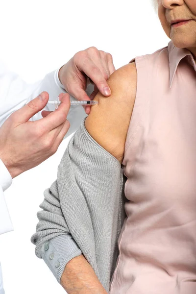 Vista recortada del médico con jeringa inyectable de vacuna de una mujer mayor aislada en blanco - foto de stock