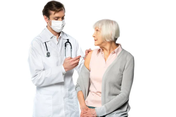 Senior Patient sieht Arzt in medizinischer Maske während Impfung isoliert auf weiß — Stockfoto