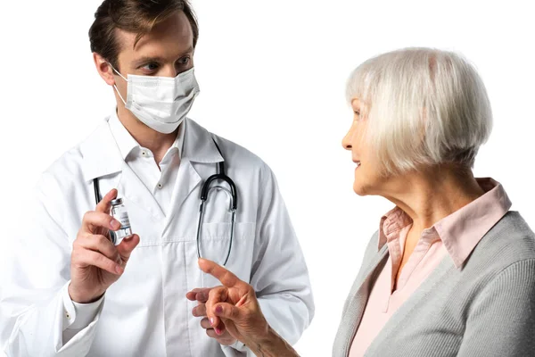 Arzt in medizinischer Maske hält Impfstoff neben lächelndem Patienten und zeigt mit weißem Finger isoliert — Stockfoto