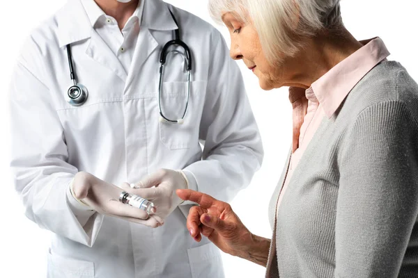 Старший пацієнт вказує пальцем біля лікаря в латексних рукавичках з вакциною та шприцом ізольовано на білому — стокове фото