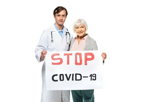 Doctor y paciente sonriente sosteniendo pancarta con letras stop covid-209 aisladas en blanco - foto de stock