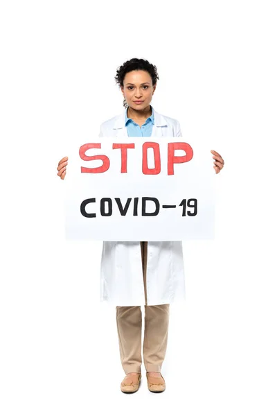 Médico afroamericano sosteniendo pancarta con letras stop covid-2019 sobre fondo blanco - foto de stock